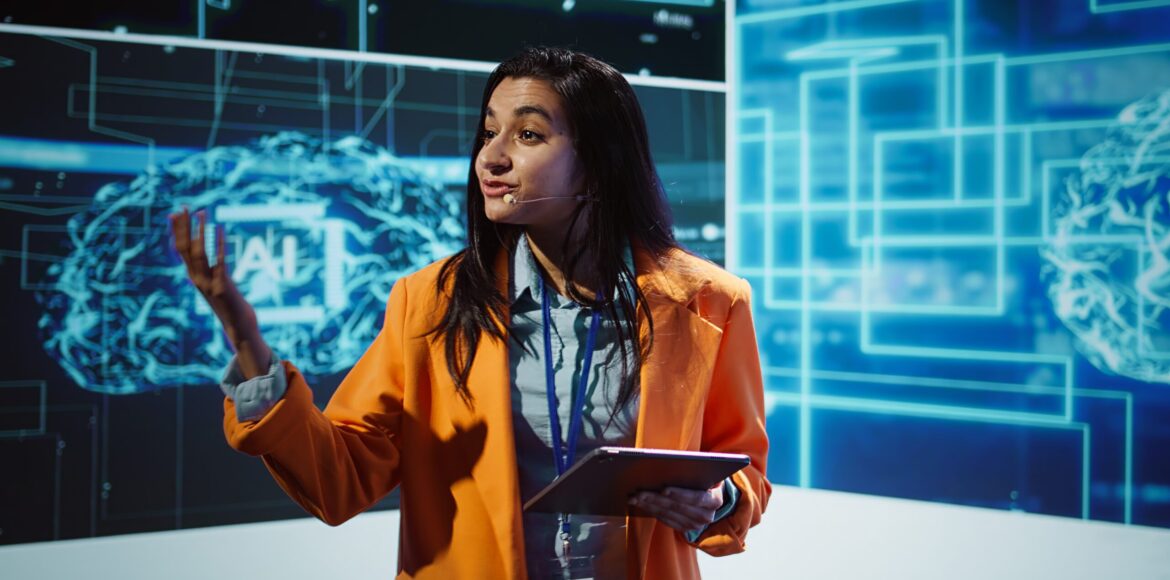 Public speaker doing presentation at tech forum event, explore ways emerging AI technologies can positively enhance companies workforce. Indian woman promoting artificial intelligence solutions